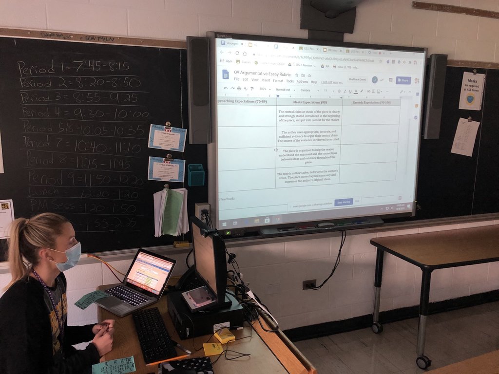 Teacher in classroom reviewing info on board